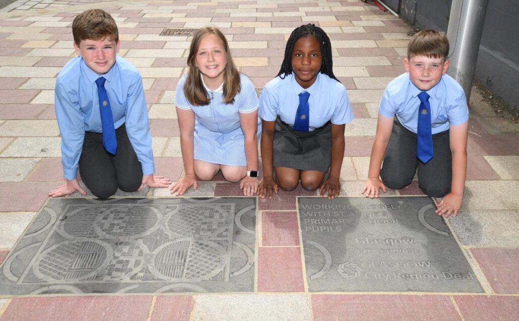 Children from a Calton Primary School were on hand to see for themselves, decorative paving plaques inspired by the artwork of former pupils which are now installed next to each of the iconic ‘The Barras’ signs. As part of recent works to regenerate the Barras Public Realm and the wider Collegelands, Calton Barras area through the Glasgow City Region City Deal, this artist-led project involving St Anne's Primary School has seen local surface designers Bespoke Atelier take inspiration for the final plaque designs from drawings and models produced by the children after they had spent time together exploring the Barras and following a series of artist-led workshops. The Barras Public Realm works is a key component of the £27m City Deal funded Collegelands Calton Barras infrastructure programme which aims to deliver an integrated, attractive and resilient neighbourhood within the inner east end of Glasgow. The programme is focusing on improving accessibility and connections to the city centre and further afield; remediating sites that have been derelict or vacant to attract development, and to build upon existing regeneration activities to improve the quality of place. Public realm work delivered at the Barras in recent times includes refurbishment of ‘The Barras’ arches; and the enhancement of local streets and spaces through high-quality resurfacing, footway widening, CCTV installation and better street lighting. Nearby junction improvements - supported by Scottish Government Community Links funding through Sustrans Scotland, also augments the area’s connectivity with the city centre and prioritises the attractiveness of active travel. Cllr Kenny McLean, City Convener for Neighbourhoods, Housing and Public Realm, said: " The Barras Public Realm project is seeking to breathe new life into this area which is superbly located as a gateway to the city centre and the east end. The improvements that have been delivered are highly positive and are expected to catalyse further investment and activity in the area. The Barras signs are looking great and the addition of these decorative plaques are a really nice touch, further contributing to the much-improved amenity of the area.” Marie Hamilton, Depute Headteacher of St Anne's Primary School said; "Our pupils had a wonderful time seeking inspiration from their visit to the Barras, and they came back to the classroom full of ideas which translated into exceptionally thoughtful artwork. It's also fantastic for the school that some of our former pupils were able to directly influence the creative process, resulting in these beautiful pieces of street art inlaid next to each of the Barras signs.” Yvonne Elliott-Kellighan, Co-Founder of Bespoke Atelier said; "The children from St Anne's have been integral to the creative process, and their keen observations of the Barras when on-site, inspired many of our design ideas. I am delighted to see the plaques now in place and I hope that the children are proud of the long-lasting influence their school has had on the local streetscape". UK Government Minister for Scotland Iain Stewart said: "Thanks to the pupils of St Anne's Primary School for contributing their creativity and talent for these decorative plaques which look fantastic. The Barras public realm improvement works are showing what the area has to offer, and will support its revitalization by attracting jobs and investment. The UK Government is investing more than £1.5 billion into City Region and Growth Deals across Scotland, helping communities to build back better from the pandemic." Finance and Economy Secretary Kate Forbes said: “It’s fantastic to see further progress in the Barras Public Realm project, which is regenerating the area for the benefit of residents, business and visitors, while also improving connections to the rest of the city and beyond. The Scottish Government is a full partner in the Glasgow City Region Deal, contributing £500 million over 20 years. The investment in this project through the Deal will contribute to the region’s economic recovery by creating jobs and providing the commercial infrastructure to support and attract businesses to Glasgow and the surrounding areas. It also encourages active travel, supporting walking and cycling infrastructure in the area.” Both the UK and Scottish Governments are providing the Glasgow City Region local authorities with £500million each in grant funding for the Glasgow City Region City Deal.