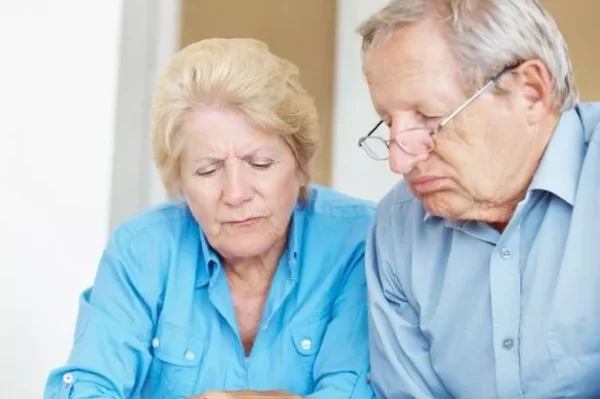 Unhappy older couple calculating their monthly expenses at home