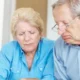 Unhappy older couple calculating their monthly expenses at home