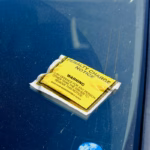 A yellow penalty charge notice stuck to a car windscreen