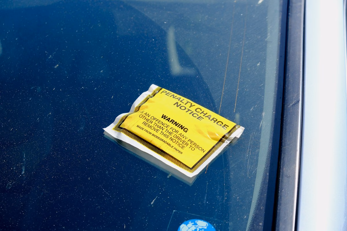 A yellow penalty charge notice stuck to a car windscreen