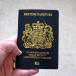 A hand holding a dark blue British passport