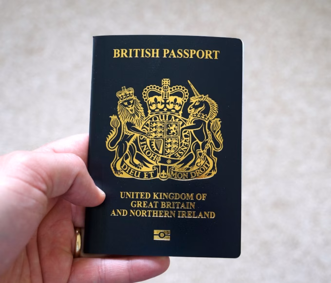 A hand holding a dark blue British passport