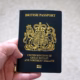 A hand holding a dark blue British passport