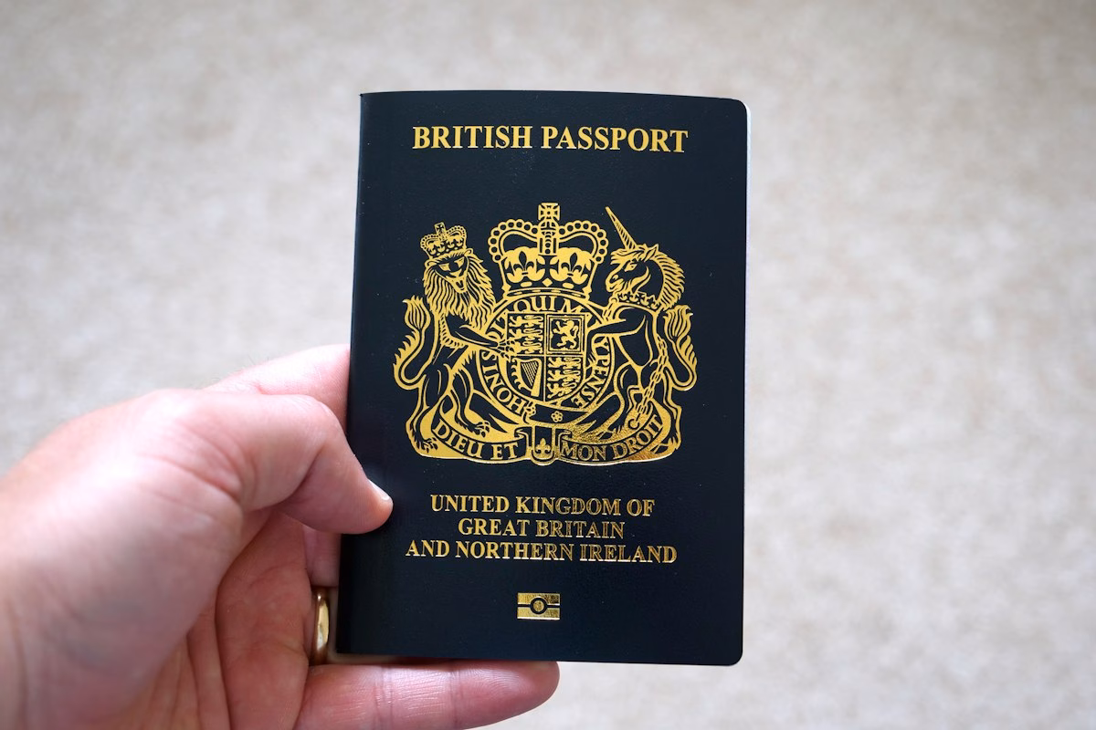 A hand holding a dark blue British passport