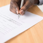 A person signing a paper document with a fountain pen