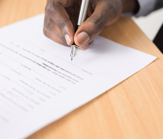 A person signing a paper document with a fountain pen