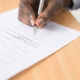 A person signing a paper document with a fountain pen