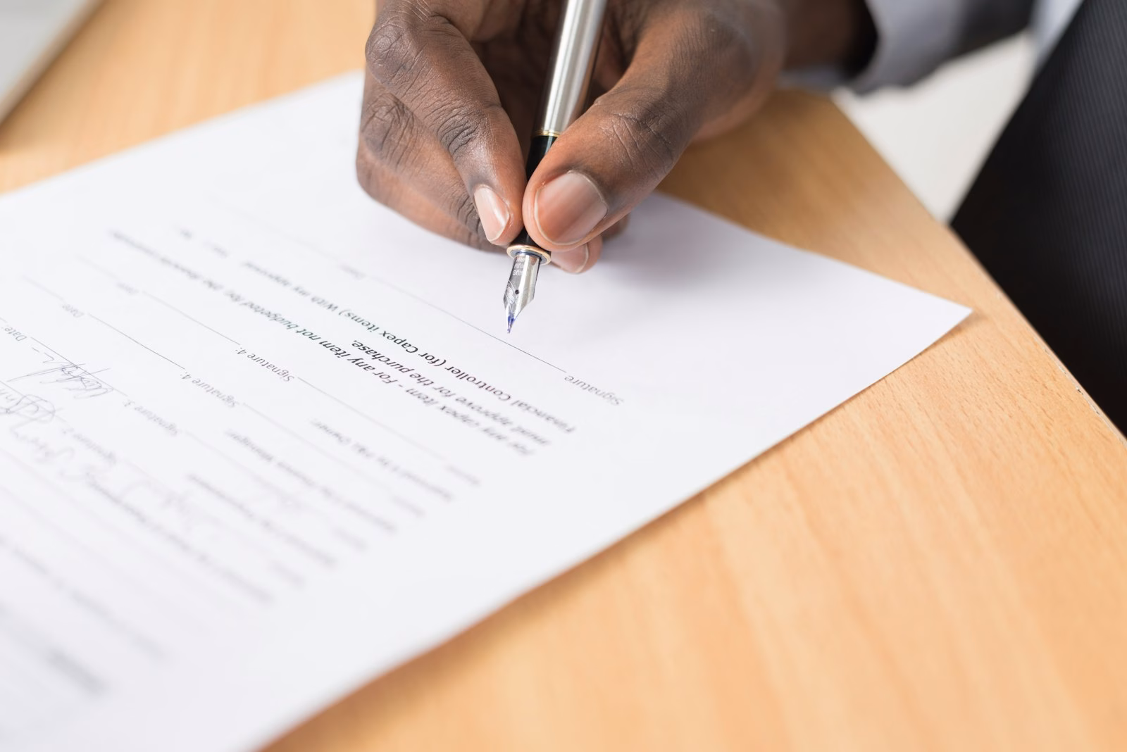 A person signing a paper document with a fountain pen