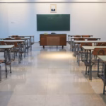 An empty classroom with rows of desks and a chalkboard