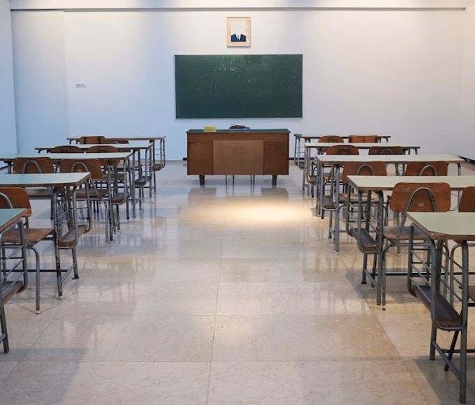 An empty classroom with rows of desks and a chalkboard